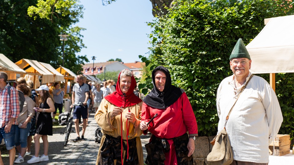 Utklädda jycklare står på medeltida marknad.