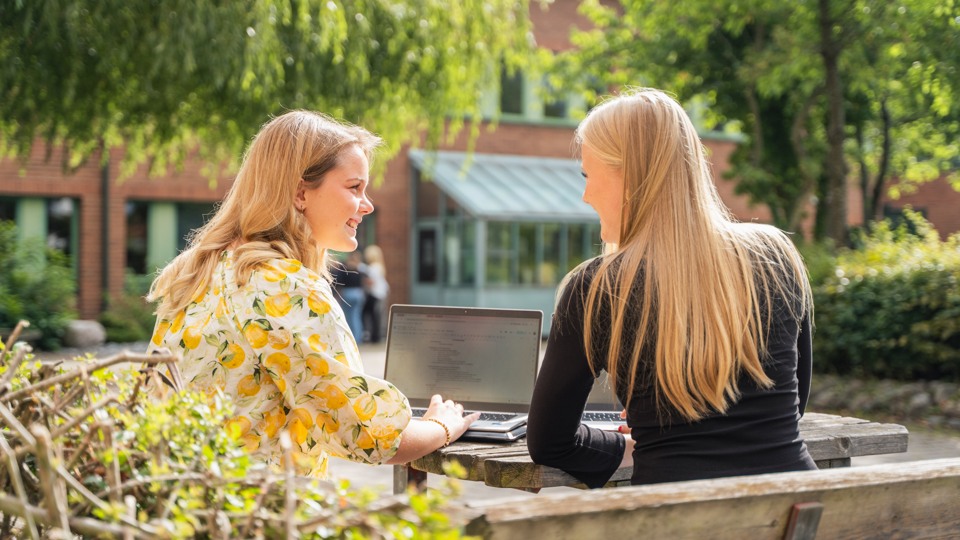 Två elever tittar på varandra framför entrén på skolgården