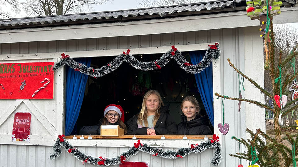 Tre tjejer i tomteluvor står i kiosken och säljer fika
