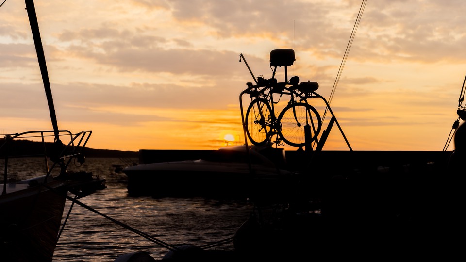 Solnedgång på Hanö. En segelbåt i Hanö hamn har en cykel lastad i aktern.