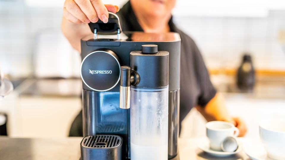 En kvinna brygger kaffe i en espressomaskin