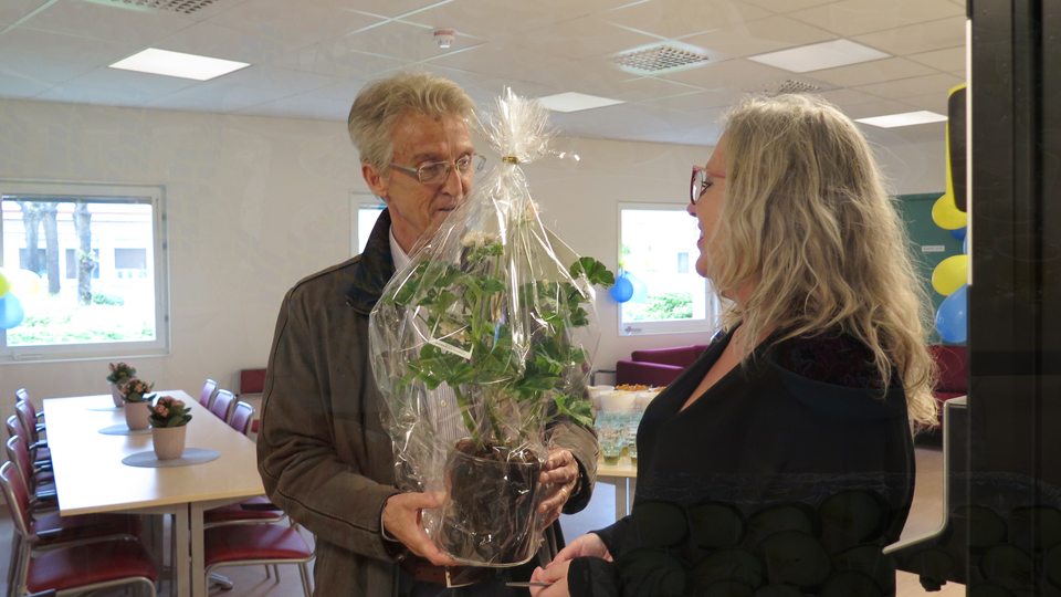Robert Lindén (SD) ordförande i omsorgsnämnden lämnar över en blomma till enhetschef Kith Mårtensson. Foto: Sölvesborgs kommun.