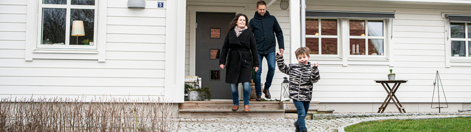 En familj med två vuxna och ett barn framför sitt nybyggda hus i stadsdelen Ljungaviken i Sölvesborg.