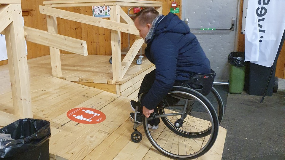 En man som sitter i rullstol kör upp på en ramp till en kiosk i Sölveshov som är ishallen i Sölvesborg. 