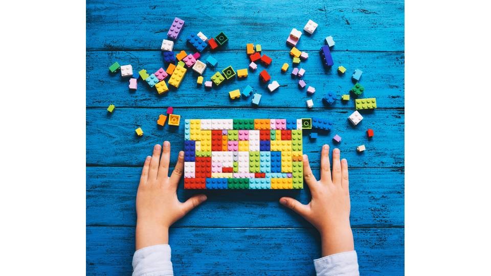 Barn som bygger med legoklossar i olika färger.