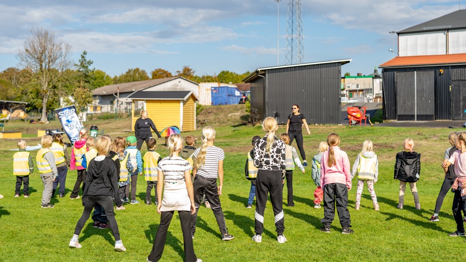 barn dansar på en stor fotbollsplan en solig dag.