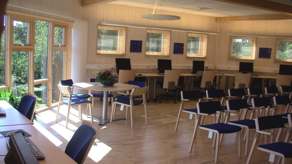 En ljus och fräsch lokal studielokal men datorer och sittplatser, inredd med möbler i ljust trä