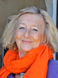 En leendes medelålders kvinna i ljust hår och en orange scarf runt halsen.