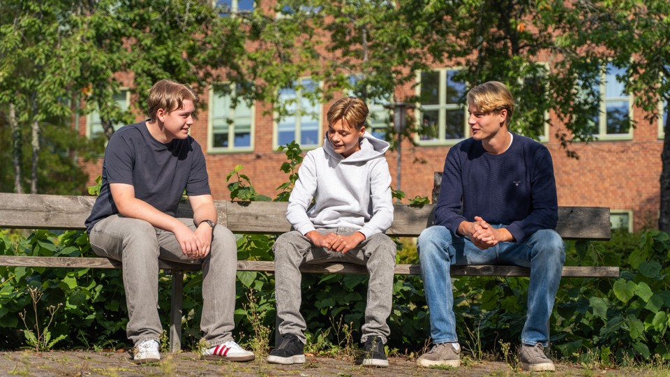 Tre elever sitter på en bänk