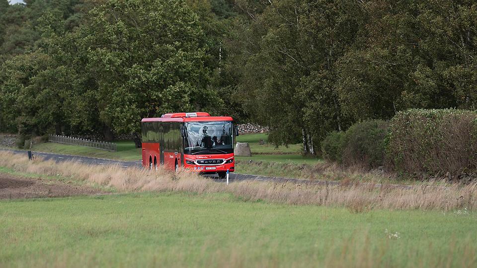 En av Blekingetrafikens röda bussar som kör på en landsväg. Foto.