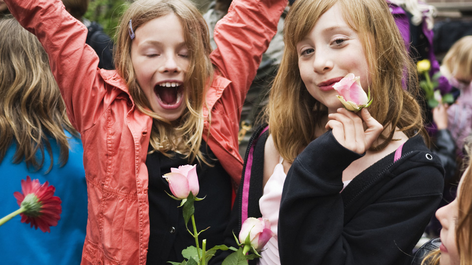 Glada barn på skolavslutning med rosor i händerna. 