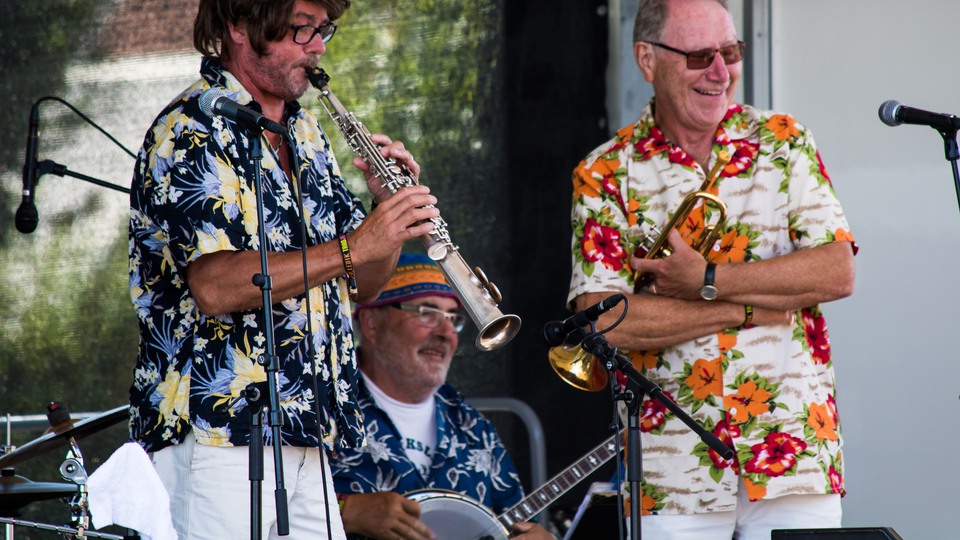 Tre män spelar jazz på scen iklädda färgglada skjortor