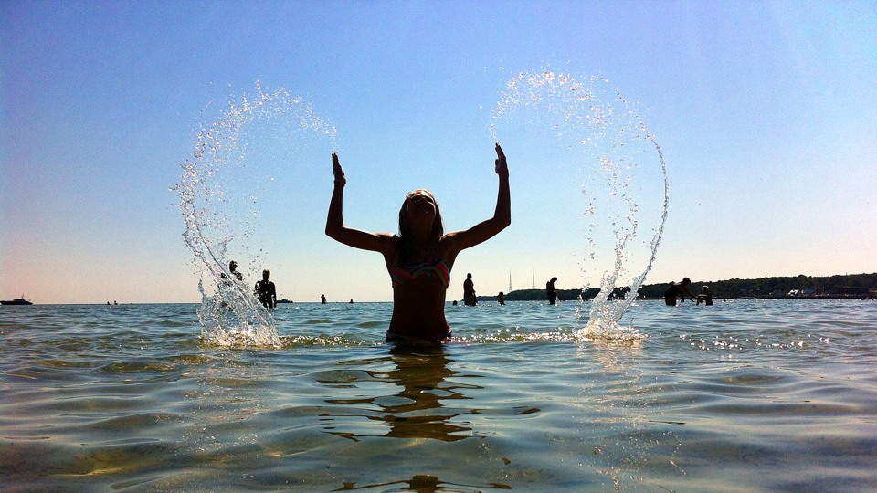 En flicka badar och skvättar med vattnet så det format ett hjärta i luften.
