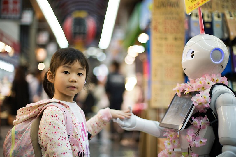 Skolbarn håller hand med en robot