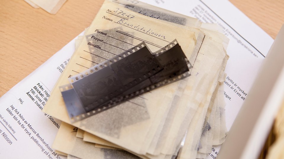 Arkiverade papper, dokument och negativ till fotografier ligger på ett bord i kommunarkivet 