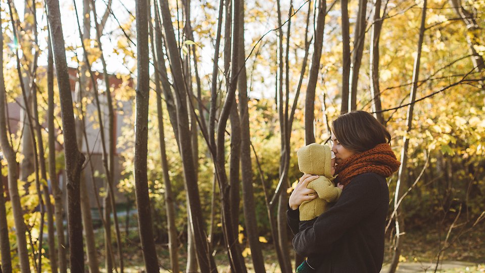 Mamma med spädbarn med skogsbakgrund